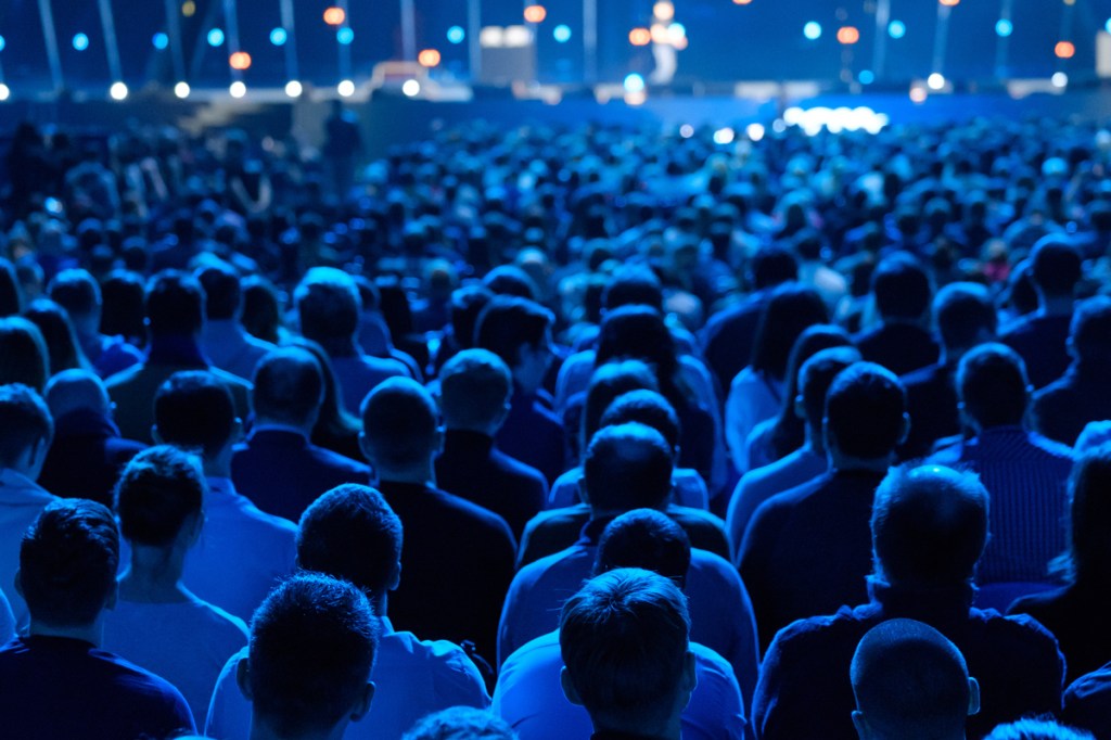 An overhead view of a full standing crowd at a business event, where automated commission payments could help to save planners valuable time.