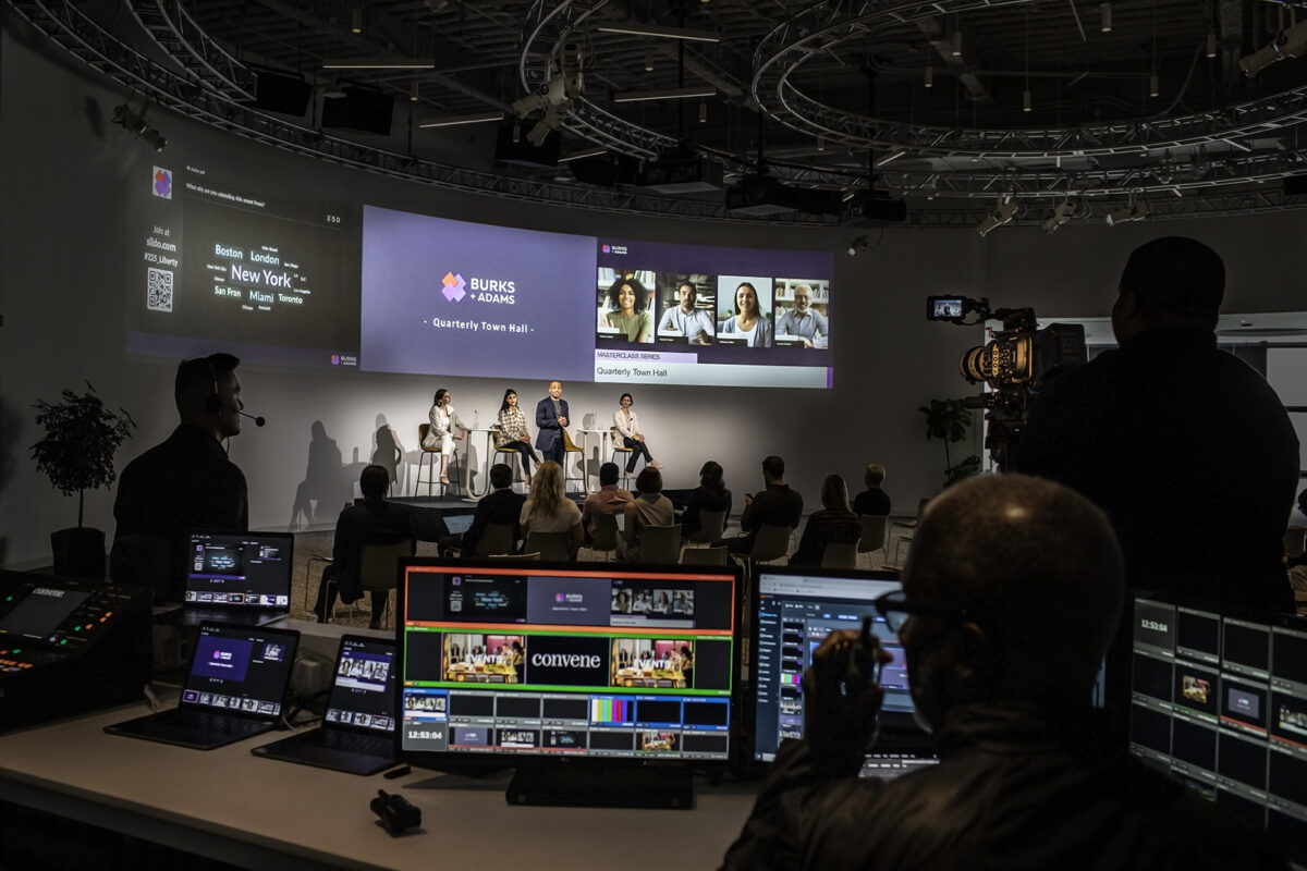 View of a conference taking place in a high-tech venue with projectors, cameras and sound equipment