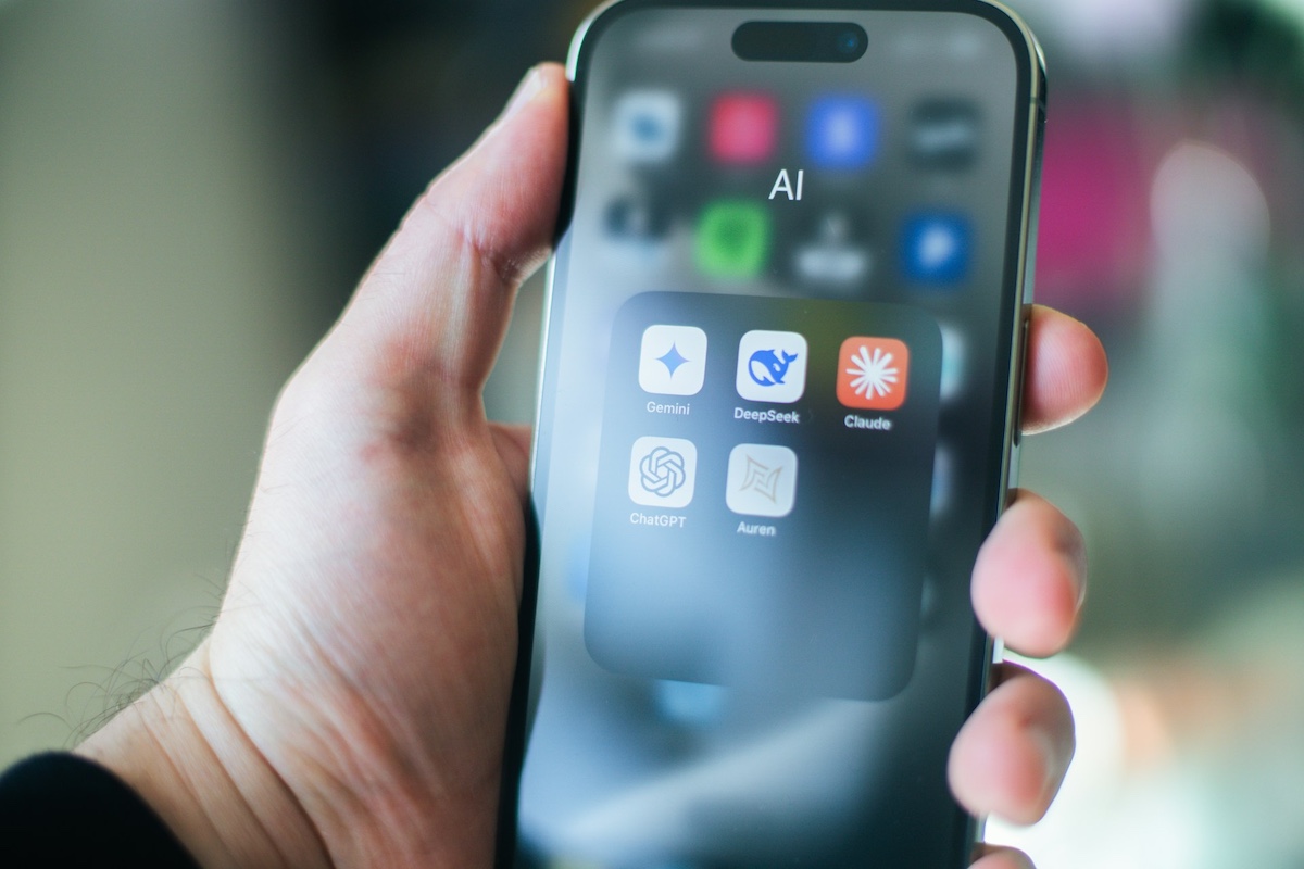 Man holding iPhone with AI apps on the screen