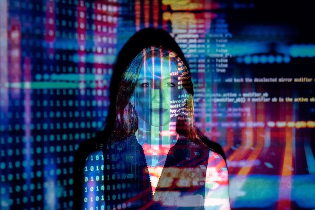 Screen with code projected onto a woman standing